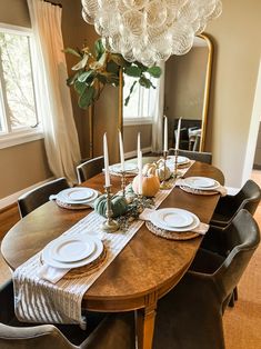 a dining room table set with plates and place settings