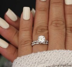 a woman's hand with white nails and a ring on her finger, holding a diamond