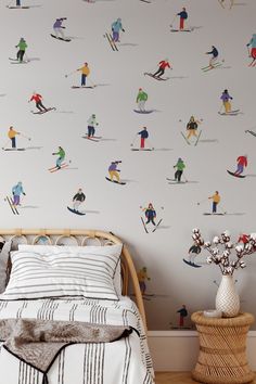 a bed room with a neatly made bed and a wallpaper covered in skiers