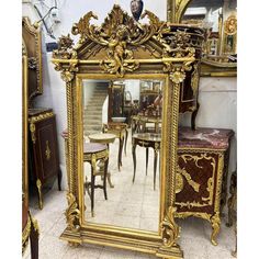 an ornate gold framed mirror sitting on top of a floor next to tables and chairs