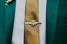 a man wearing a green suit with a yellow tie and flower boutonniere