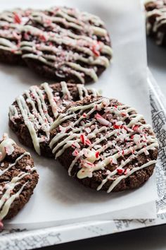 chocolate cookies with white icing and candy canes are on a piece of paper