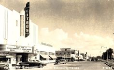 an old black and white photo of cars parked in front of a movie theater on the street