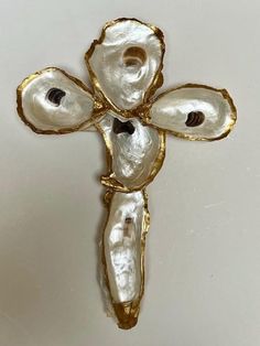 a cross made out of oyster shells on a white surface with gold trimmings