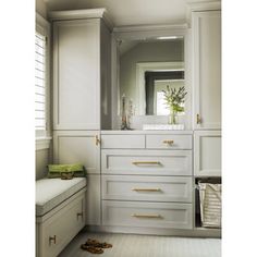 a bathroom with white cabinets and drawers