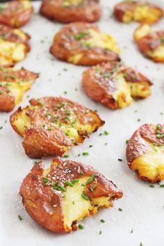 small pizzas with cheese and chives are on a baking sheet, ready to be eaten