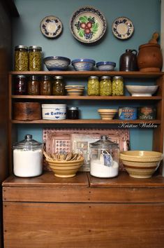 an old dresser with bowls and jars on it's shelves, next to other items