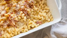 macaroni and cheese with bacon in a white casserole dish on a towel