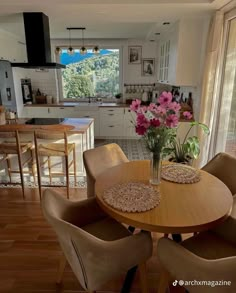 a table with four chairs around it in front of an open kitchen and dining area