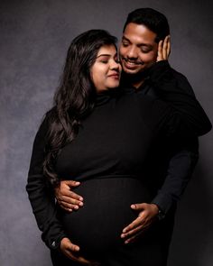 a pregnant couple hugging and smiling for the camera