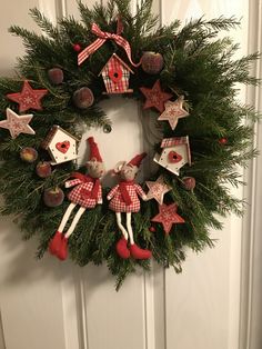 a christmas wreath with red and white ornaments hanging from the front door, decorated with santa's helpers