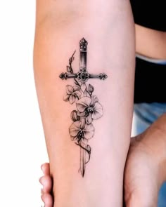 a cross and flowers tattoo on the arm