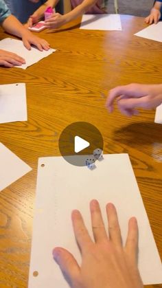 a group of children sitting around a wooden table with paper on top of it and one child's hand