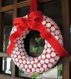 a red and white wreath hanging from the side of a window with words describing it