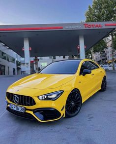 a yellow mercedes cla parked in front of a gas station