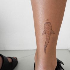 a small tattoo on the leg of a woman's foot with a whale tail