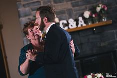 a man and woman hugging each other in front of a fireplace