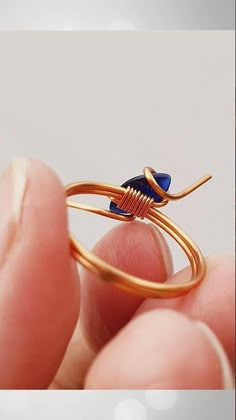 a person holding a gold ring with blue stones in it's middle and the top part of their finger