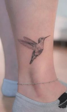 a small tattoo on the ankle of a woman's foot with a hummingbird