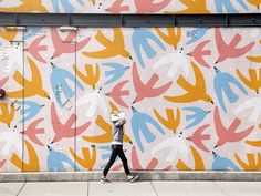 a person walking past a colorful wall with birds painted on it