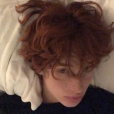 a woman with red hair laying in bed under a white blanket on top of her head