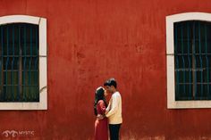 a man and woman standing in front of a red building