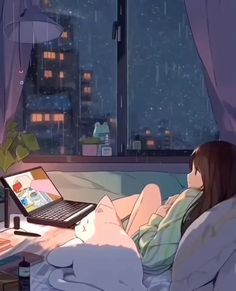 a woman laying in bed with a laptop on her lap and looking out the window