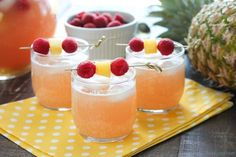 three glasses filled with fruit and garnish on top of a yellow place mat