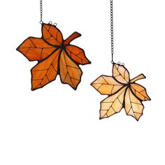 two stained glass leaves hanging from chains on a white background, one is orange and the other is brown