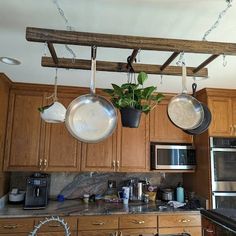 pots and pans hanging from the ceiling in a kitchen with wooden cabinets, an oven and microwave