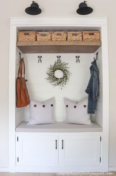 a coat rack with two coats and some baskets on top of it next to a bench