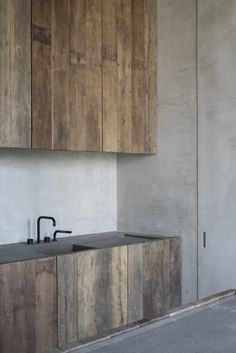 an empty kitchen with wooden cabinets and black faucet on the counter top in front of it