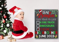 a baby dressed as santa claus sitting next to a christmas tree