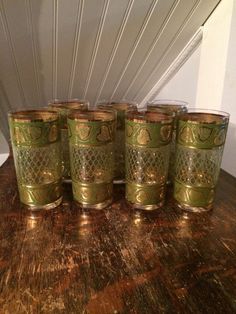 five green glass cups sitting on top of a wooden table