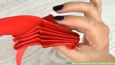 a woman's hand holding red paper with black nails