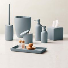 bathroom accessories including soap dispenser, toothbrush holder and soap dish are arranged on a white surface