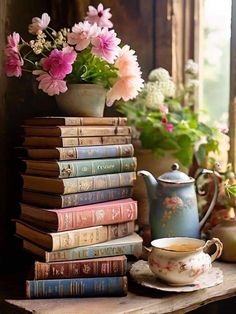 a stack of books sitting on top of a table next to a vase filled with flowers