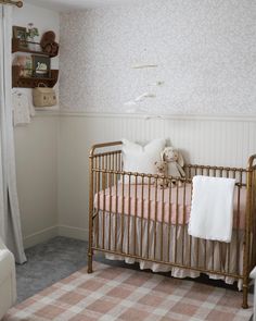 a baby's crib in the corner of a room with pink and white bedding