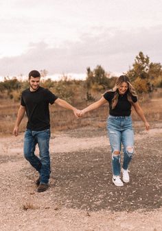 two people holding hands while walking in the dirt