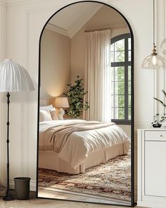 an arched mirror in the corner of a room with a bed and lamp on it