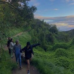 three people walking up a hill on a trail