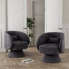 two gray chairs sitting on top of a hard wood floor next to a potted plant