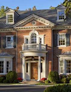 a large red brick house with white trim and black shutters on the front door