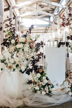 two white vases filled with flowers and greenery on a wedding ceremony table setting