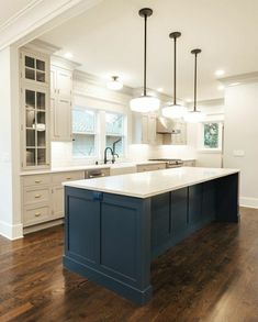 a large kitchen with an island in the middle and two pendant lights hanging from the ceiling