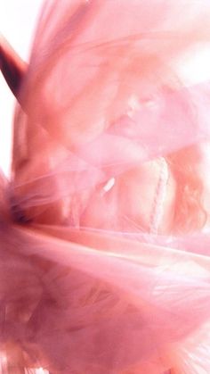 blurry photograph of a woman with her hair blowing in the wind and wearing a pink dress