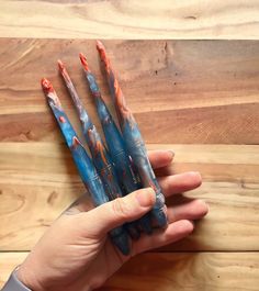 a hand holding three blue and red toothbrushes on top of a wooden table