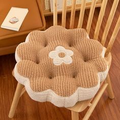 a wooden chair with a flower shaped cushion on top of it next to a table