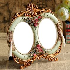 two oval frames with flowers on them sitting on top of a table next to books