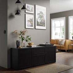 a living room with two pictures on the wall and a plant sitting on top of a cabinet